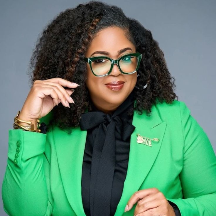 Kyra — green blazer, glasses, slightly different angle headshot